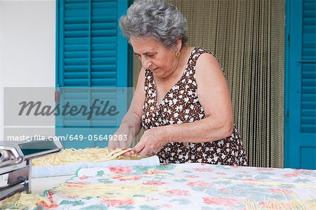 Older woman making pasta with roller
