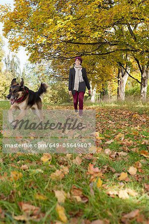 Smiling woman walking dog in park