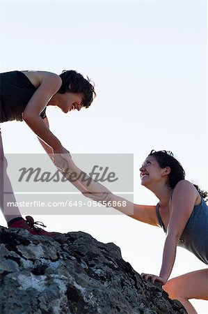 Hikers helping each other climb rock