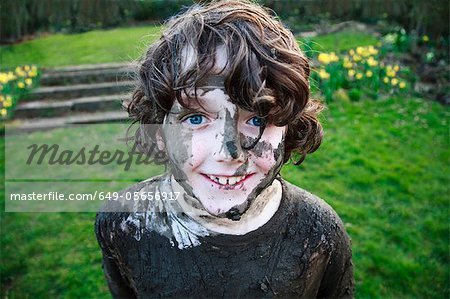 Boy's smiling face covered in mud