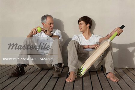 Father and son with cricket bat on patio