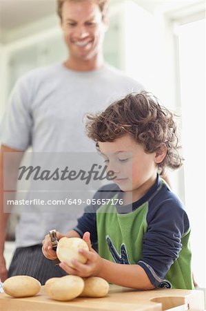 Boy peeling potatoes in kitchen