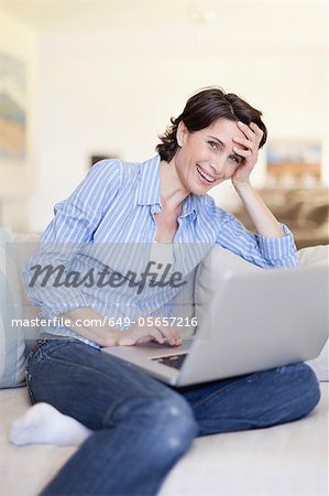 Smiling woman using laptop on couch Smiling woman using laptop on couch