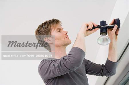 Man installing light fixture in house