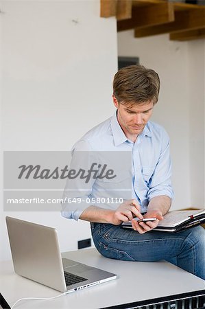 Businessman using cell phone in office Businessman using cell phone in office