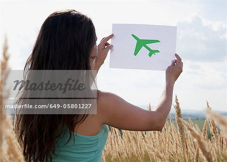 Woman holding picture of airplane in sky