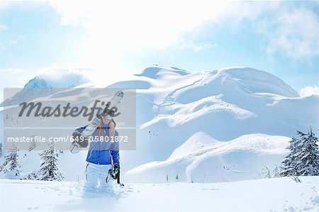 Man carrying snowboard in snow