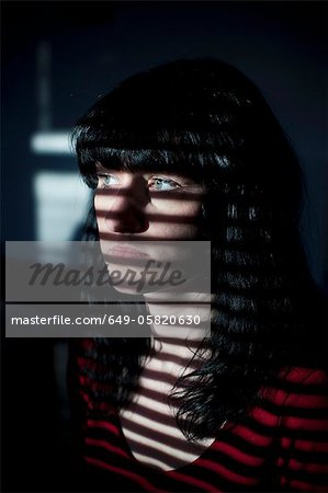 Woman standing in blinds shadow Woman standing in blinds shadow
