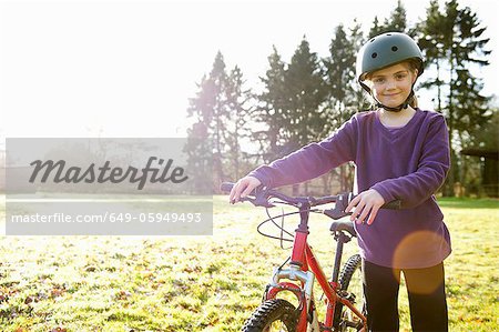 Girl walking with bicycle in meadow
