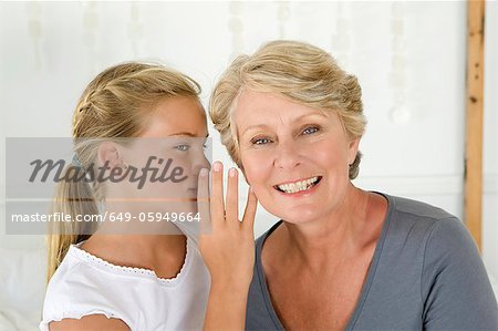 Girl whispering to grandmother