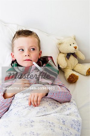 Boy with thermometer in mouth in bed