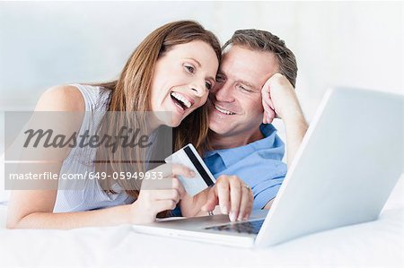 Couple shopping online on bed