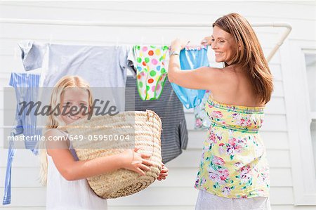 Girl helping mother hang laundry