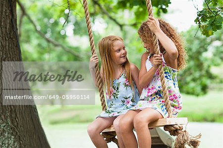 Two Girls Sharing An Tree Swing Stock Photo - Download Image Now