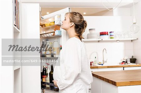 Pregnant woman searching fridge for food
