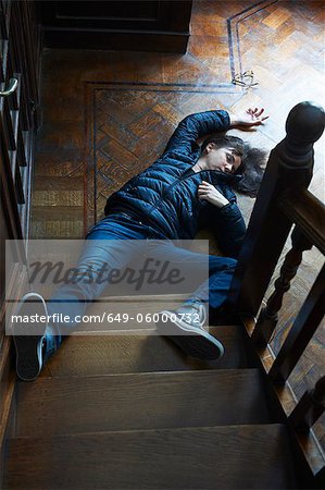 Teenage boy laying at foot of stairs
