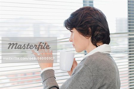 Businesswoman peering out office window