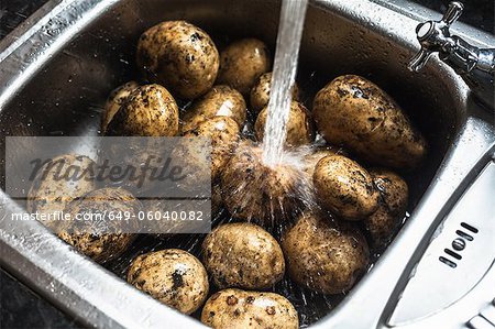 Water rinsing potatoes in sink