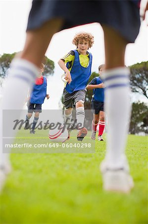 Boys playing soccer on pitch