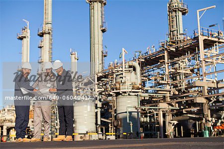 Workers with blueprints at oil refinery Workers with blueprints at oil refinery
