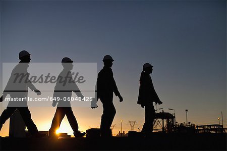 Silhouette of workers at oil refinery