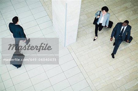 Business people rolling luggage in lobby