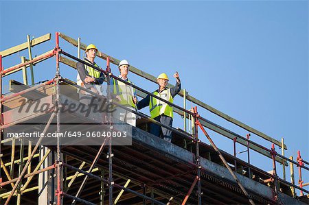 Workers standing on scaffolding on site