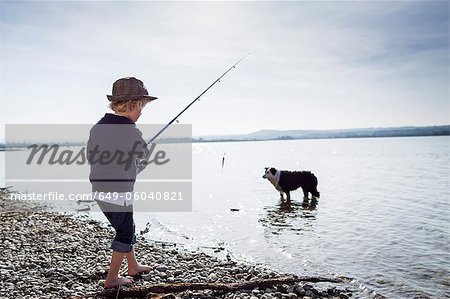 Boy fishing with dog in creek