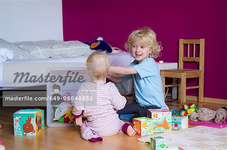 Siblings playing together in bedroom