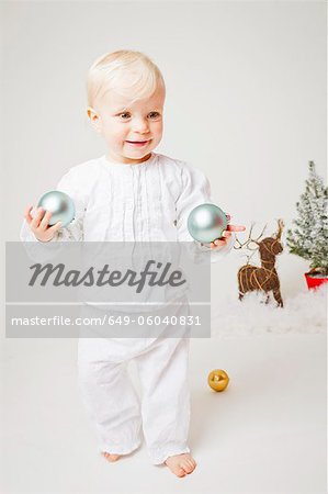 Baby girl holding Christmas ornaments