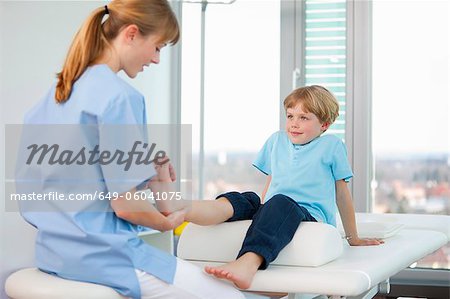 Doctor examining boys feet in office