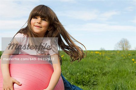 Girl playing on bouncy ball in field