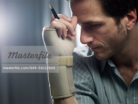 Businessman in wrist brace with pencil