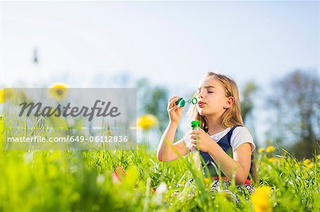 Girl blowing bubbles in field