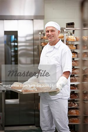 Chef carrying tray of bread in kitchen