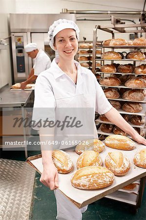 Chef carrying tray of bread in kitchen