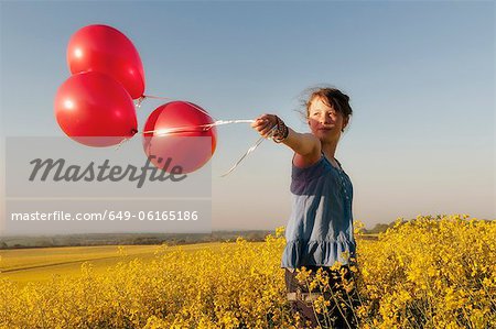 Girl carrying balloons in field