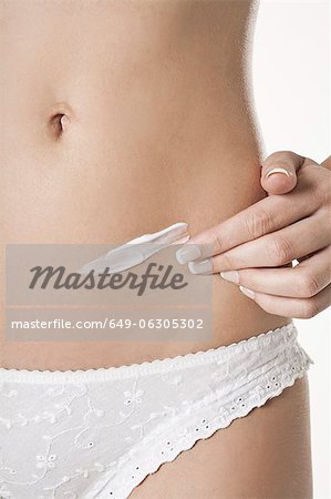 Woman rubbing lotion on belly