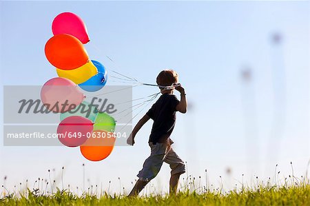 Boy with colorful balloons in grass