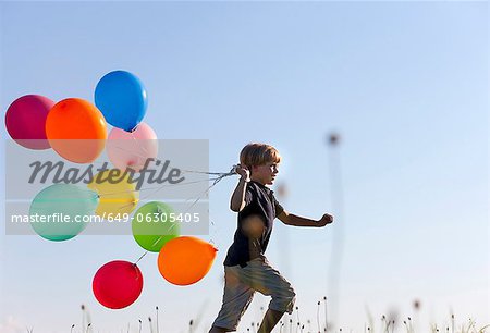 Boy with colorful balloons in grass