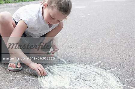 Girl drawing sun on sidewalk in chalk