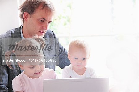 Father and children playing with laptop