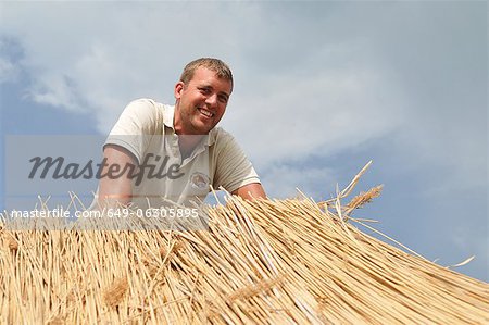 Man working on straw roof
