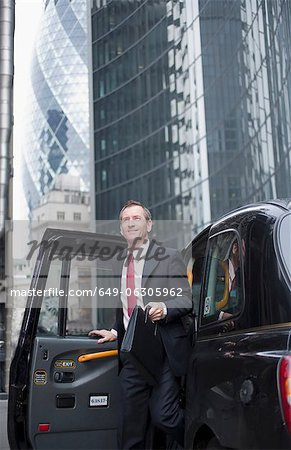 Businessman climbing out of taxi cab