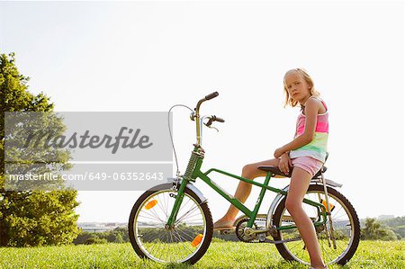 Girl sitting on bicycle in grass