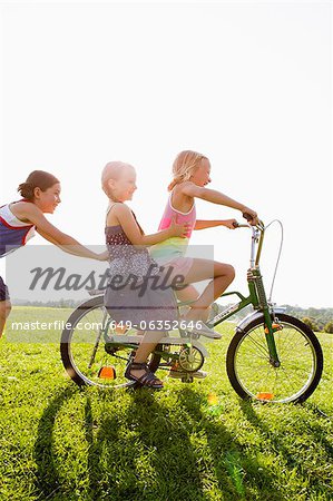 Girls playing with bicycle in grass