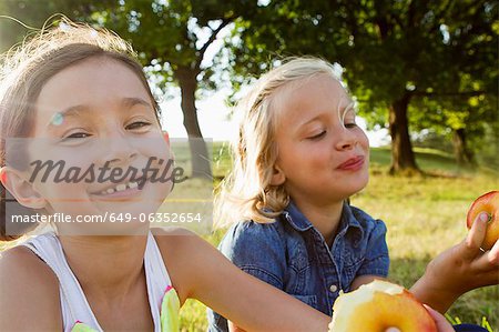 Laughing girls eating apples outdoors