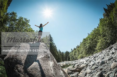 Woman with arms outstretched on rock