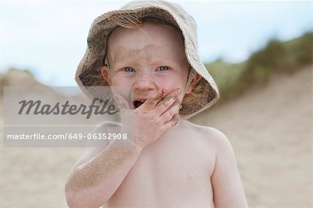 Boy covered in sand on beach