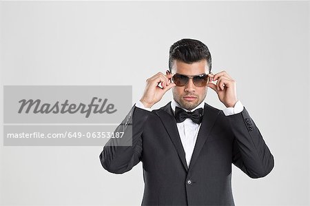 A man with a beard and sunglasses in a gray suit poses on the street to  advertise men's clothing. Advertising menswear Stock Photo | Adobe Stock